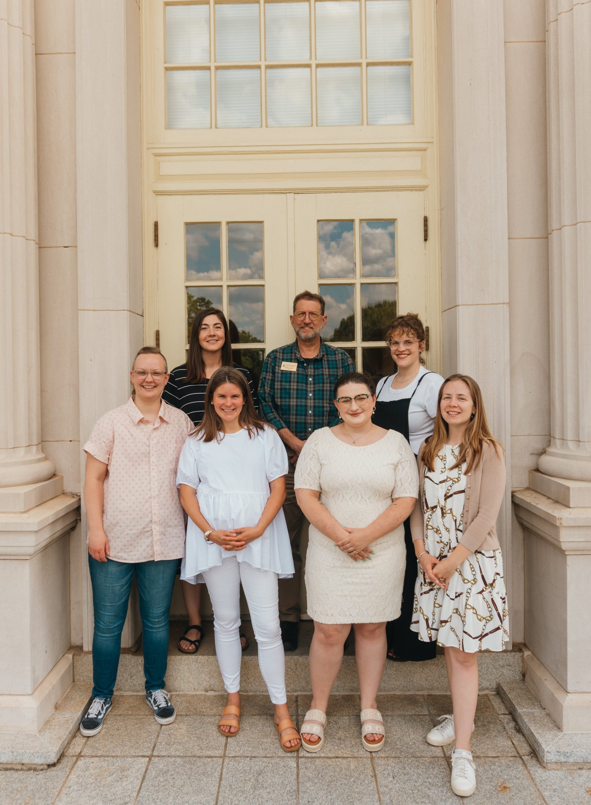 Seven people standing together in front of a set of doors