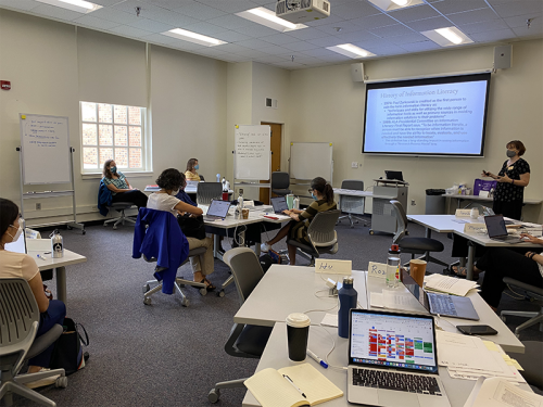 Faculty work at grouped desks during Information Literacy workshop