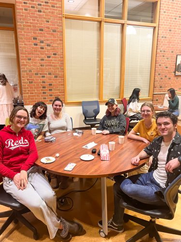 A group of six students around a table, drinking tea and eating popcorn and s'mores