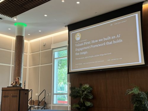 Lauren behind a podium with a slide behind her that says "Values First: How we built an AI Engagement Framework that holds the range."