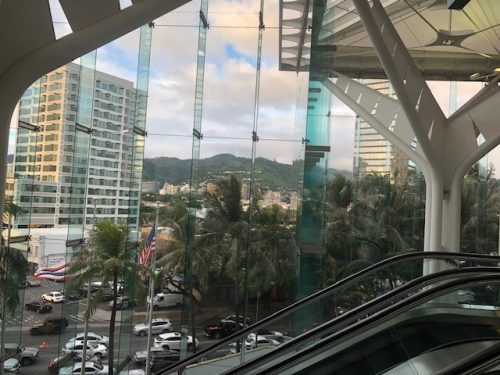 View of mountains and a tall building from inside a glass-walled convention center