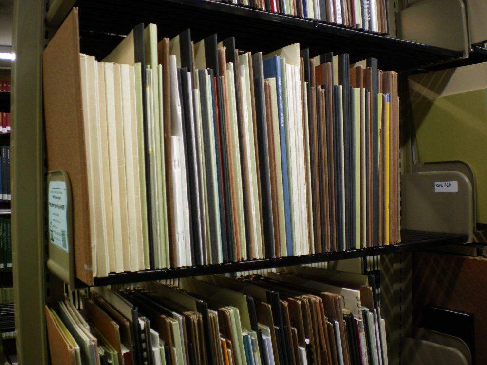 Tall, thin music scores standing on a library shelf.