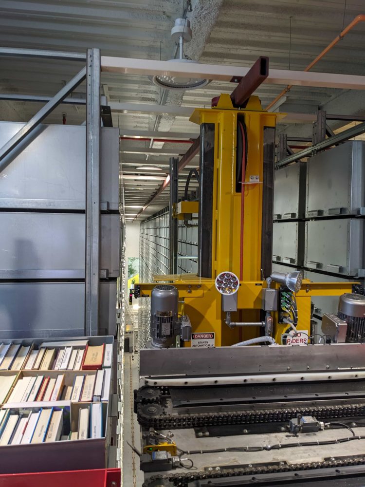 A view of the back of the Bookbot room, with the bot in the middle and shelves on either side.