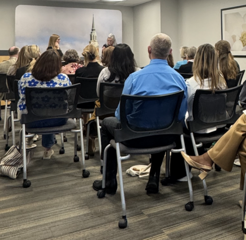 An image taken from the back of the room of author Laura Elliott being interviewed by Dean Lauren Pressley with an audience in the foreground of the image.