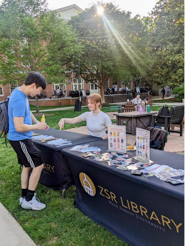 ZSR's Fellow and a student interacting at library's table at the AAPI Celebration.