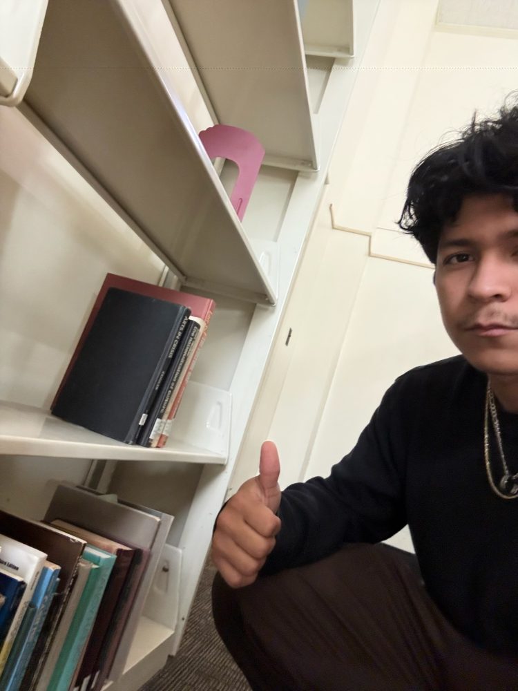 ZSR student worker Kevin Elizondo posing with a thumbs up next to the last few books to be shifted.